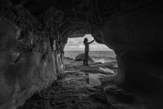 Person Exploring The Wormhole Sea Cave at Manly Beach in Black and White