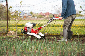 Organic farming man cultivates the ground with a tiller preparing the soil for sowing