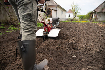 Organic farming man cultivates the ground with a tiller preparing the soil for sowing