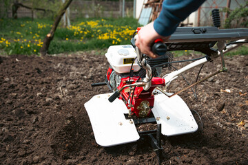 Organic farming man cultivates the ground with a tiller preparing the soil for sowing