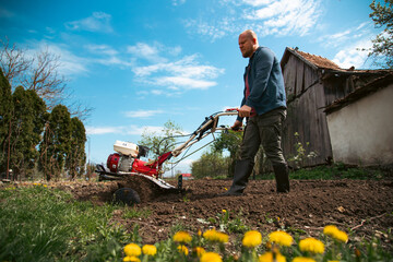 Organic farming man cultivates the ground with a tiller preparing the soil for sowing