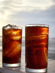 Cola drink with ice cubes and beach with blue sky