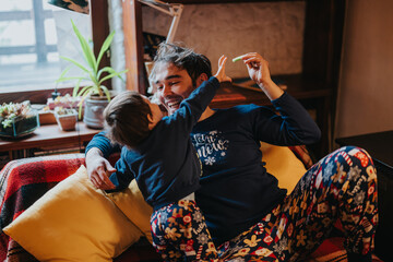 A father and child enjoy playful moments together at home, featuring a cozy, relaxed atmosphere with decorative indoor plants and a comfortable sofa.