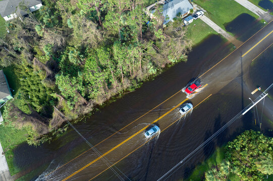 Fototapeta Hurricahe fainfall flooded Florida road with evacuating cars and surrounded with water houses in suburban residential area