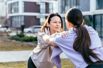 Mother and teenage daughter doing partner workout in city park