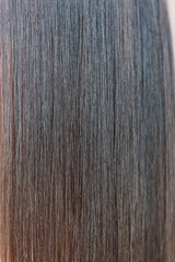 Naklejka premium Close-up of a brunette woman's beautiful long smooth healthy hair. Vertical photo