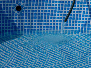 A pool with a blue tile floor and a hose running into it