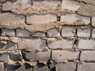 A wall made of bricks with a lot of cracks and holes