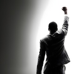 Motivated businessman celebrating success, confident man in suit raising fist towards light, inspiring achievement and determination.