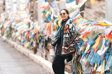 Obraz premium Woman traveler explores Leh Ladakh, India, walking beside colorful Tibetan prayer flags, embracing Himalayan culture, spiritual atmosphere on adventurous mountain journey