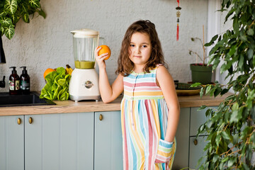 Cute little girl making healthy drink green smoothie on home kitchen