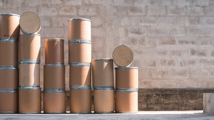 Group of the old brown paper buckets (paper tank) stacked on the ground for reuse and recycle in front of concrete wall background in industrial yard area