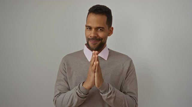 Young man smiling confidently against an isolated white wall background expressing charm and satisfaction