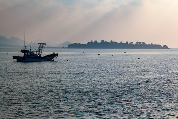 idyllic seascape with sunbeams and fishing boat