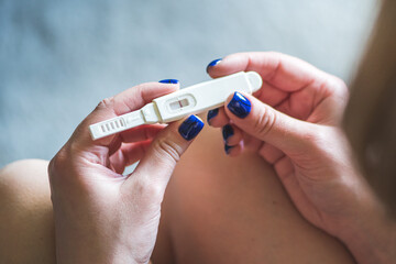Young blonde girl sitting and looking at a negative pregnancy test, top view