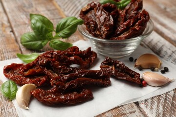 Delicious sun dried tomatoes and spices on wooden table, closeup