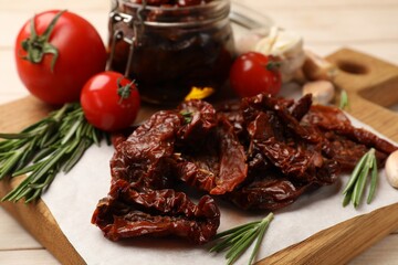 Tasty sun dried tomatoes and fresh vegetables on light wooden table, closeup
