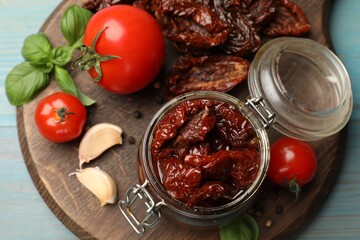Tasty sun dried tomatoes, fresh vegetables and peppercorns on light blue wooden table, top view