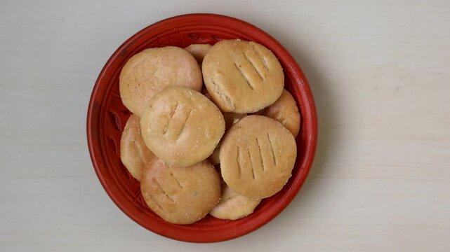 Tasty, crispy Bakarkhani (Baqarkhani), a traditional Bengali flatbread from Mughlai cuisine, served on a clay plate. Delicious top-view food shot on a light wooden surface.