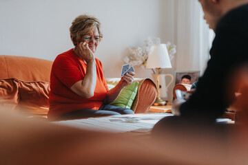 An elderly woman enjoying a card game seated in a warm home environment, sharing quality time with a loved one, promoting relaxation and bonding.