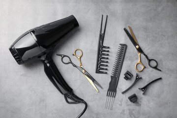 Different hairdresser's tools on grey table, flat lay