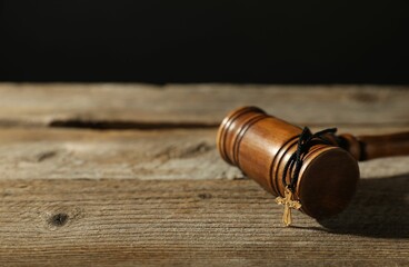 Judge's gavel and cross on wooden table, closeup. Space for text