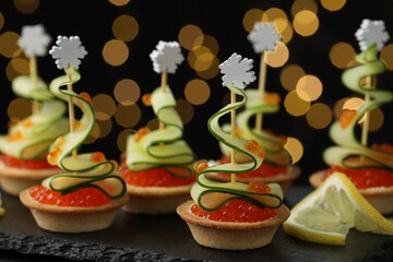 Tasty canapes on table against dark background with blurred lights, closeup. Bokeh effect