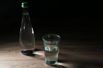 Fresh water in glass and bottle on wooden table