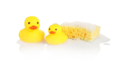 Cute rubber ducks and sponge with foam on mirror surface against white background