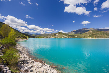 Obraz premium Turquoise waters of Castillon Lake reflecting the blue sky in Castellane, France