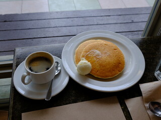 Flat lay of hotel breakfast with pancakes and coffee on marble table. Warm natural tones, cozy morning atmosphere. Ideal for food blogs, lifestyle content, hospitality, and travel visuals.