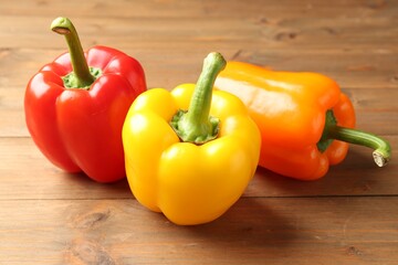Ripe colorful bell peppers on wooden table, closeup