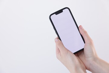 Woman holding smartphone with blank screen on white background, closeup. Mockup for design