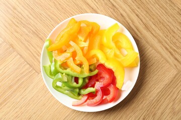 Slices of fresh colorful bell peppers on wooden table, top view