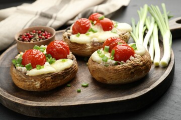 Tasty stuffed mushrooms served on black table, closeup