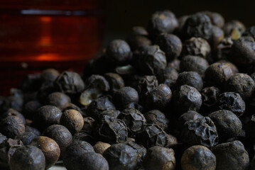 Black peppercorns piled up with red container in background