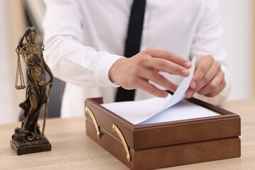 Judge working and Lady Justice figure on desk indoors, selective focus