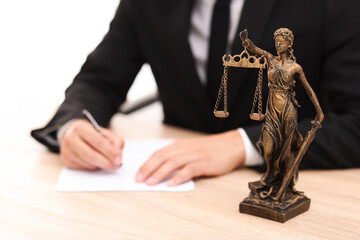 Judge working and Lady Justice figure on desk indoors, selective focus