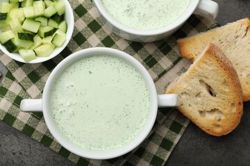 Tasty cucumber soup served on grey table, flat lay