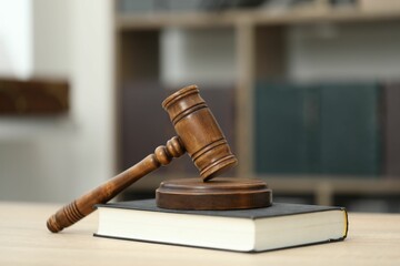 Judge's gavel and book on wooden table in office, closeup