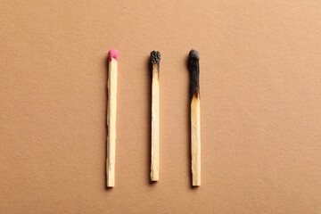 Burnt and whole matches on beige background, flat lay