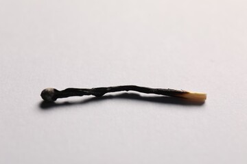 One burnt match on grey background, closeup view