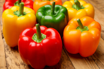 Fresh colorful bell peppers on wooden table, closeup