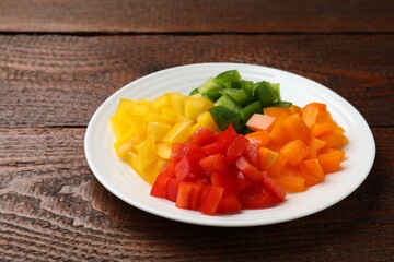 Cut colorful bell peppers on wooden table, closeup