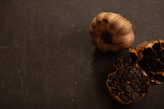 Garlic bulb sliced in half showing cloves on dark benchtop