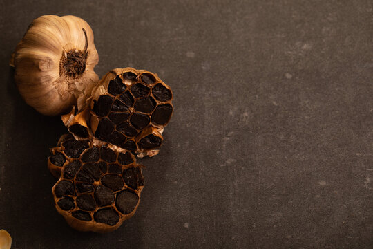 Garlic bulb sliced in half showing cloves on dark benchtop