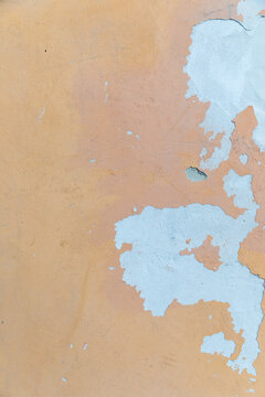 Weathered ochre coloured rendered wall with blue paint chips