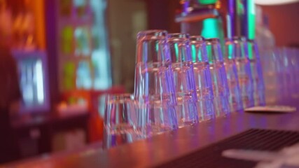 A lively bar scene presenting a splendid display of stacked glasses set against a vibrant, colorful backdrop. Night club