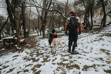Group of friends spending time together in a snow-covered park on a cold winter day, interacting...