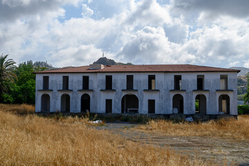 An unfinished residential building stands against a mountainous backdrop featuring the iconic Ataturk silhouette, a symbol seen across Northern Cyprus.